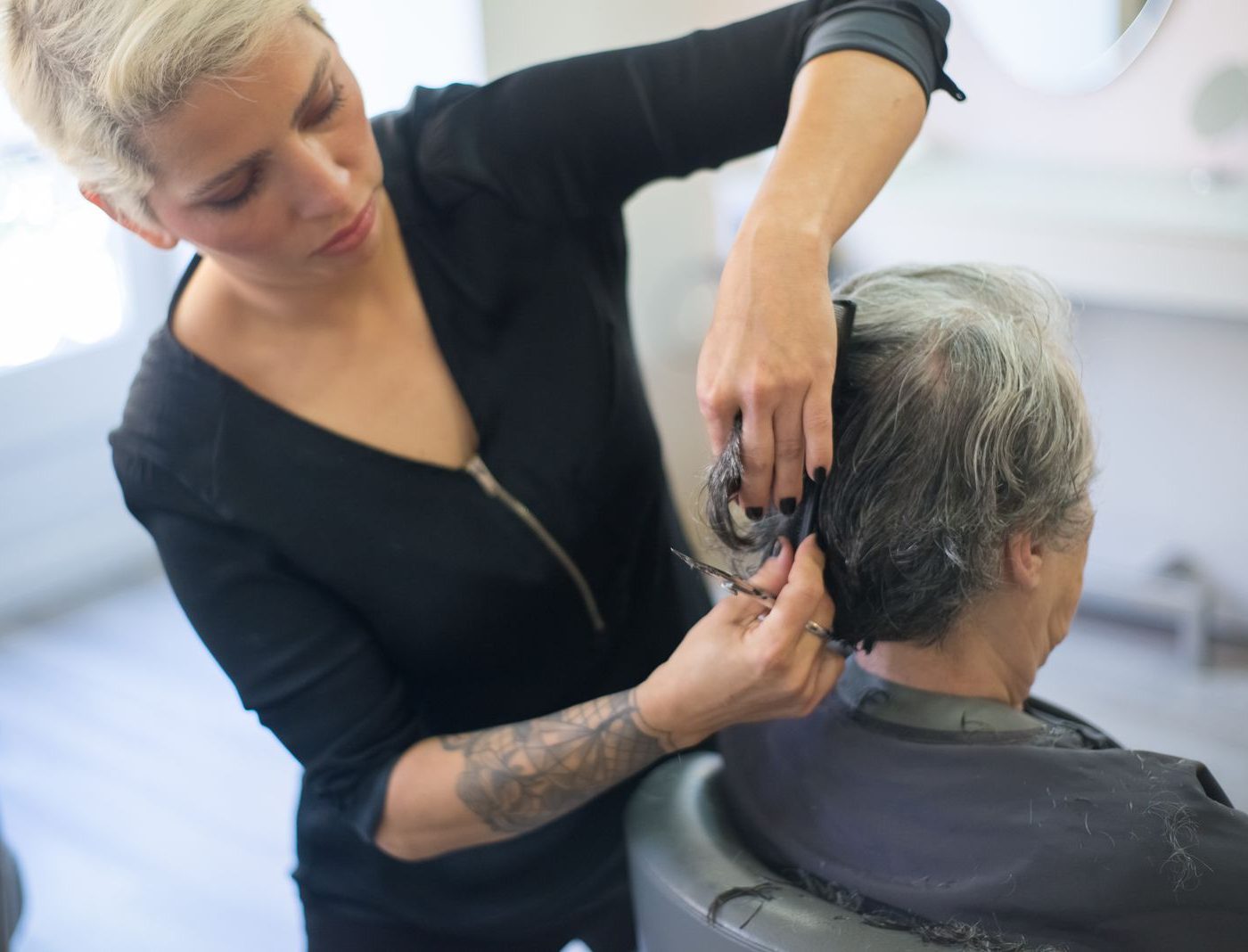 Friseurin arbeitet konzentriert und mit sichtbarem Handwerk am Haar einer Kundin