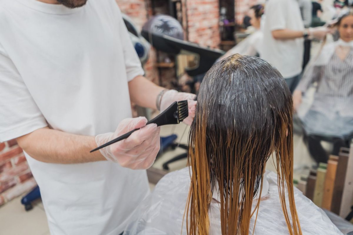 Stylist arbeitet konzentriert an einer Coloration im warmen Salonlicht