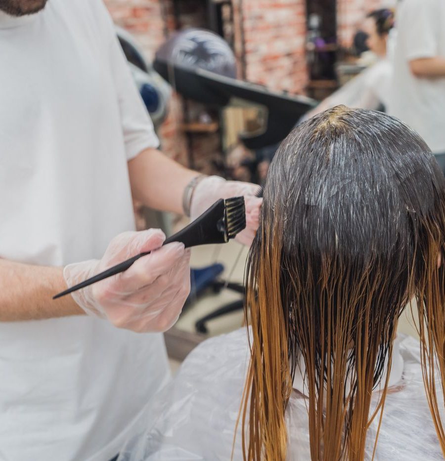 Stylist arbeitet konzentriert an einer Coloration im warmen Salonlicht